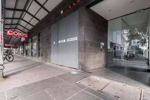 A commercial building with a sign for Coles, a closed door labeled 'Sprinkler Booster,' and a bicycle parked outside.