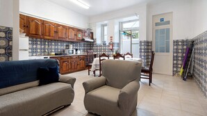 Una sala de estar con sofá y sillón, una cocina con muebles de madera y salpicadero de azulejos.