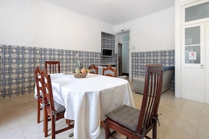 Un comedor con una mesa redonda, sillas y una cesta de frutas.
