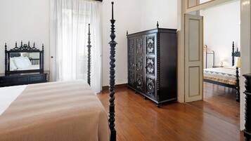 A bedroom with a four-poster bed, a dark wooden cabinet, and a mirror on the wall.