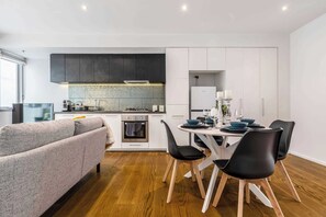 Uma cozinha moderna com área de refeições, um sofá e uma mesa posta para dois.