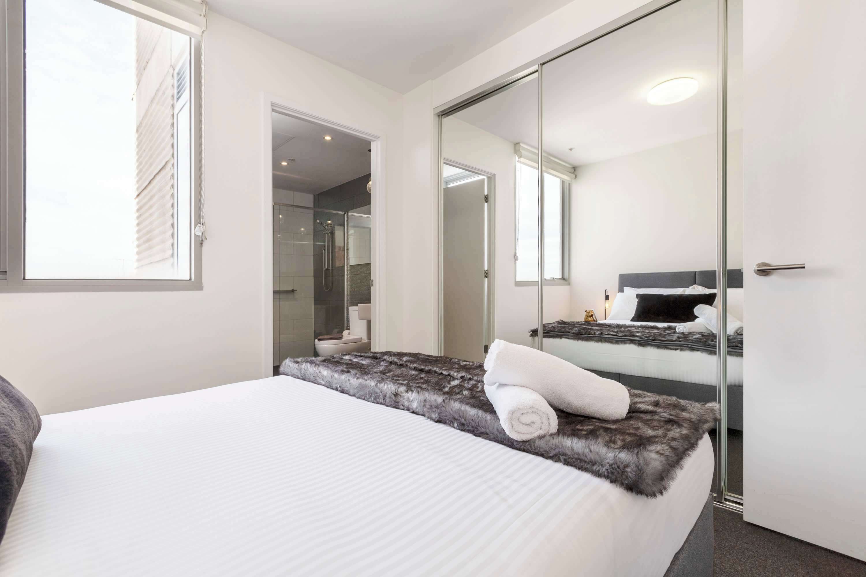 Een moderne hotelkamer met een groot bed, een douchecabine van glas en uitzicht op de stad.