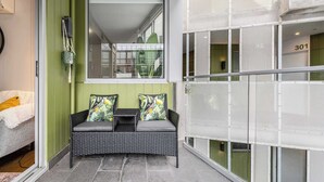 Un balcon avec un canapé en osier, une petite table et une chaise.