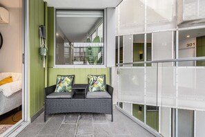 A balcony with a wicker sofa, a small table, and a chair.