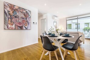 A dining area with a round table, black chairs, and a large abstract painting on the wall.