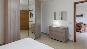 A bedroom with a bed, a dresser, a mirror, and a wardrobe. - Apartment 'Ca' Graziosi Cuori' with Mountain View, Shared Garden and Wi-Fi (Bagnone)