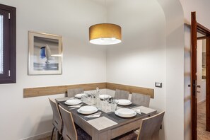 Un comedor con una mesa dispuesta para cuatro personas, un cuadro en la pared y una lámpara colgante moderna.