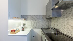 A modern kitchen with a white countertop, a built-in oven, a stainless steel sink, and a tiled backsplash. - Apartment 'Ca' Graziosi Fiori' with Mountain View, Shared Garden and Wi-Fi (Bagnone)