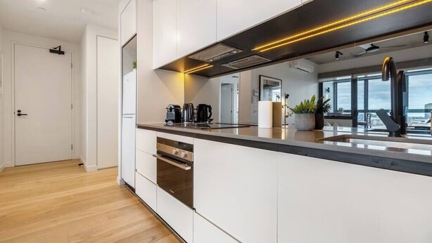A modern kitchen with white cabinetry, a stainless steel oven, and a black countertop.