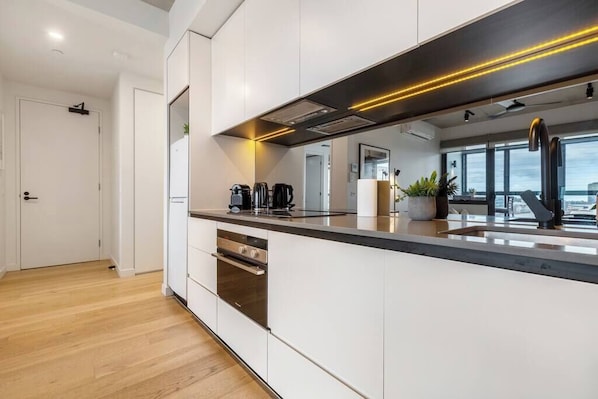 A modern kitchen with white cabinetry, a stainless steel oven, and a black countertop.
