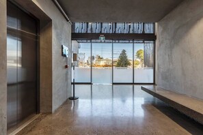 Um interior moderno com piso de concreto, uma porta de vidro que dá para o exterior e um corrimão de metal.