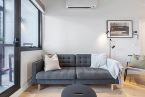 A modern living room with a grey sofa, a round coffee table, and a framed picture on the wall.