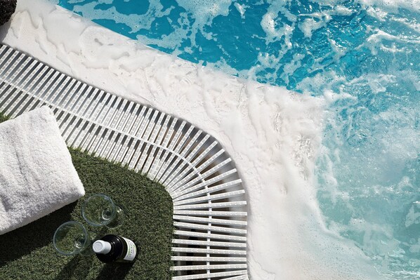 A poolside area with a sun lounger, a towel, and a bottle of wine.