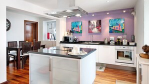 Een moderne keuken met witte kasten, een centraal eiland en een eethoek met houten stoelen.