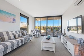 A modern living room with a sofa, chairs, a coffee table, and a TV.