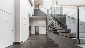 Un interior moderno con una escalera, un panel indicador de incendios y un diseño minimalista y limpio.