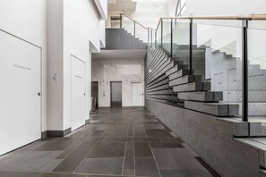 A modern interior with a staircase, a fire indicator panel, and a clean, minimalist design.