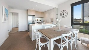 Una cocina moderna con armarios blancos, una mesa de comedor de madera y un ventanal con vistas.