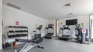 Un gimnasio con cintas de correr, elípticas y mancuernas.