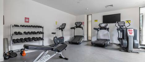 A gym with treadmills, elliptical machines, and dumbbells.