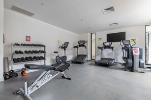 A gym with treadmills, elliptical machines, and dumbbells.