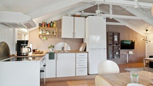 A compact kitchen with white cabinets, a coffee machine, and a dining area with a table and chairs. - 3 bedroom beautiful home in Samsø (Samsø)