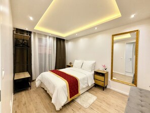 Restful retreat with a neatly made bed, bedside table, and large mirror.