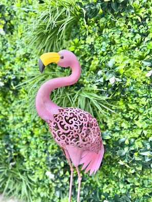 Stunning pink flamingo sculpture amidst lush greenery.