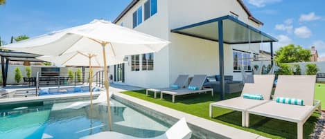 A modern house with a swimming pool, outdoor seating, and a covered patio area.