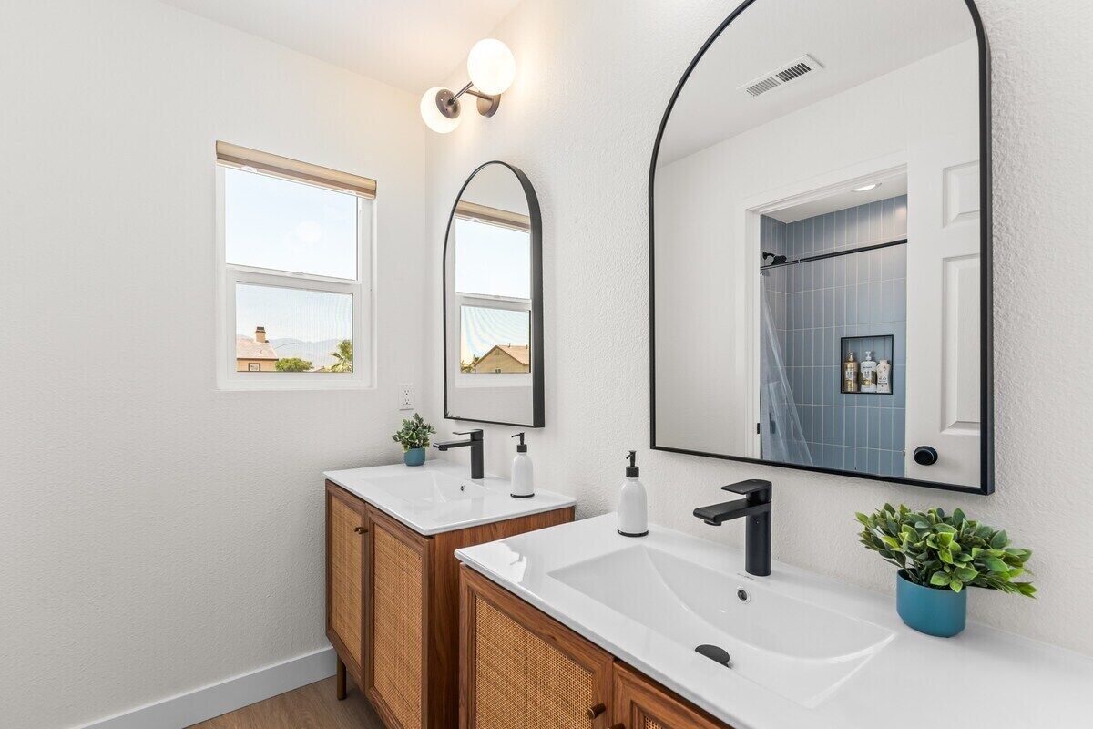 Une salle de bain moderne avec deux lavabos, un grand miroir et une fenêtre.