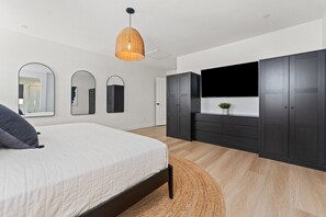 Ein Schlafzimmer mit einem Bett, einem großen Spiegel, einem Kleiderschrank und einem Fernseher an der Wand.