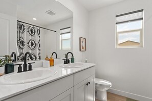 Ein modernes Badezimmer mit zwei Waschbecken, einer Toilette und einer Duschkabine mit Sonnendruck.