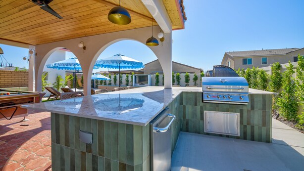 An outdoor kitchen area with a built-in grill, seating, and a pool table. - Los Arcos- 7 bedrooom, sleeps 19 Pool Home (Coachella)