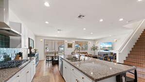 A modern kitchen with granite countertops, white cabinetry, and a central island. - Los Arcos- 7 bedrooom, sleeps 19 Pool Home (Coachella)