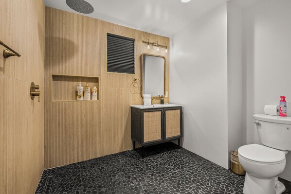 A modern bathroom with a wooden vanity, a mirror, and a toilet.