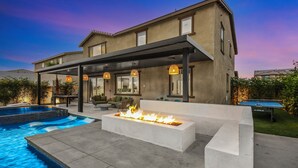 A modern house with a swimming pool, outdoor seating, and a fire feature. - Escape to this newly remodeled 7-bedroom desert retreat designed for relaxation and fun. Enjoy a large resort-style pool and spa, a fully stocked kitchen, spacious game room, and outdoor games perfect for group play under endless blue skies. Whether (Coachella)
