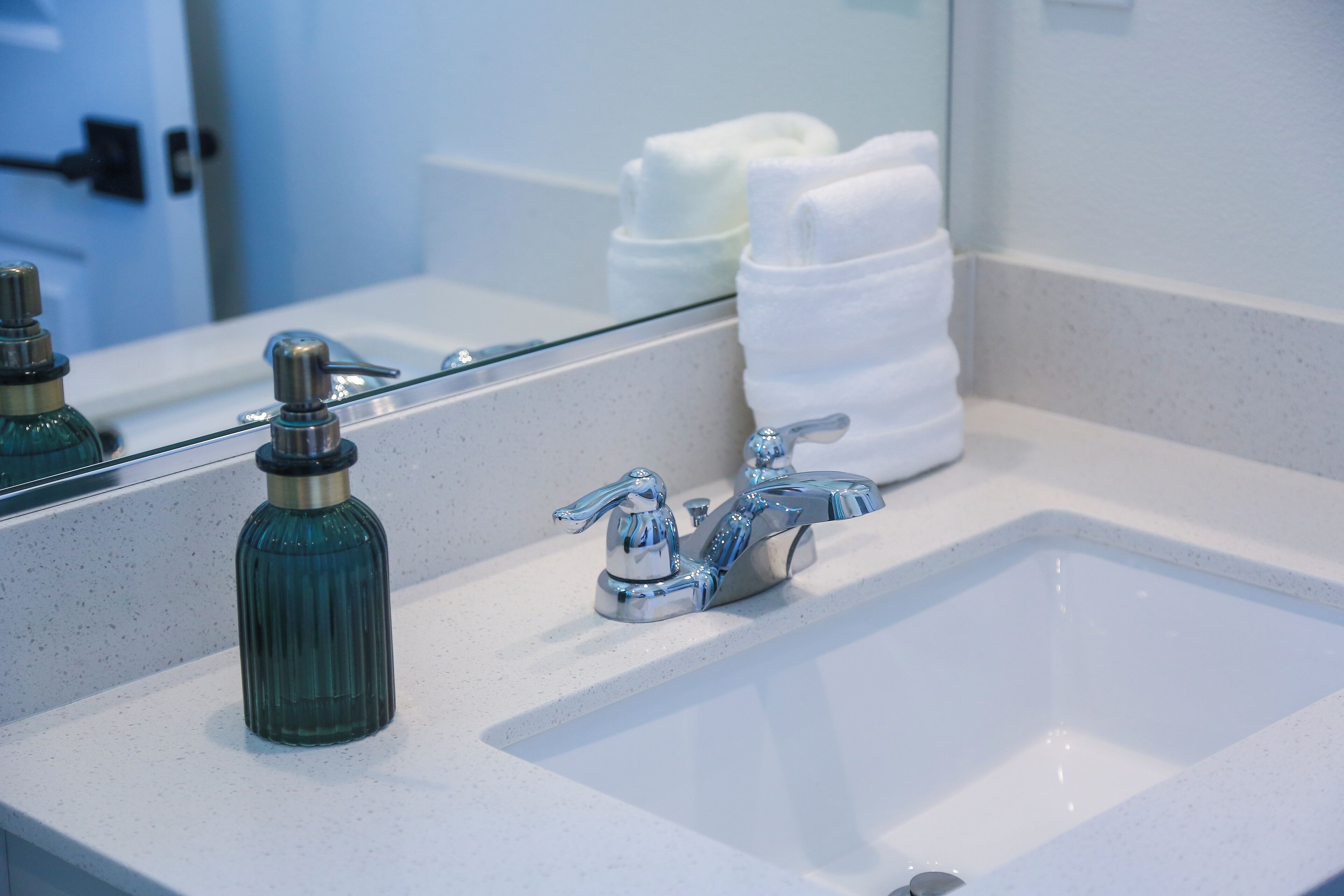 A bathroom sink with a chrome faucet and a green soap dispenser.