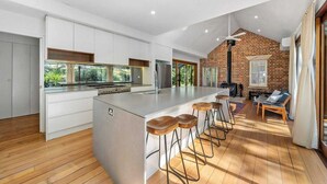 A modern kitchen with a large island, bar stools, and a fireplace. - Waterfront Retreat - Kayaks, Heated Pool, Firepit and so much more!  (Lower Portland)