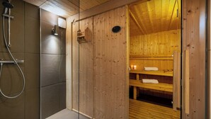 A wooden sauna with a glass door, a shower area, and a shelf with towels. - Chalet Paravis - La Clusaz stay for 9 sauna and games room - OVO Network (La Clusaz)
