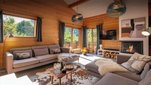 A modern living room with a sofa, a coffee table, and a fireplace. - Chalet Paravis - La Clusaz stay for 9 sauna and games room - OVO Network (La Clusaz)