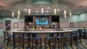 A bar area with a counter, bar stools, and a large screen displaying an underwater scene.