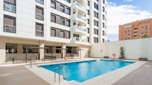Un moderno edificio de apartamentos con piscina, balcones y cielo despejado.