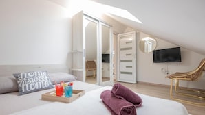 Een slaapkamer met een bed, een nachtkastje met drankjes, een stoel, een televisie en een schuifdeur.
