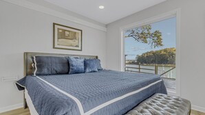Ein Schlafzimmer mit einem großen Bett, einer Kopfteil und Blick auf einen Balkon.