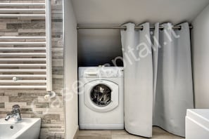 Casa de banho compacta com máquina de lavar roupa, lavatório e cortina de chuveiro.