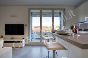 A modern kitchen with a TV, dining area, and a sliding glass door to the outside.