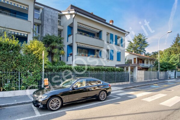 Un bâtiment moderne à deux étages, doté de balcons, avec une voiture garée devant et un ciel dégagé.