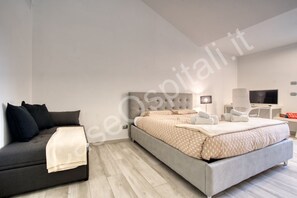 Un dormitorio moderno con cama, sofá, escritorio y televisor.