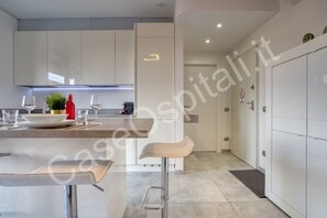 A modern kitchen with white cabinets, a bar stool, and a dining area with a table set for two.
