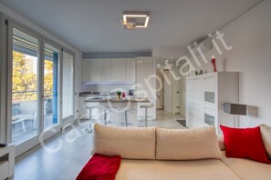 Un interior moderno con un sofá, una zona de cocina y un ventanal corredero que da a un espacio exterior.
